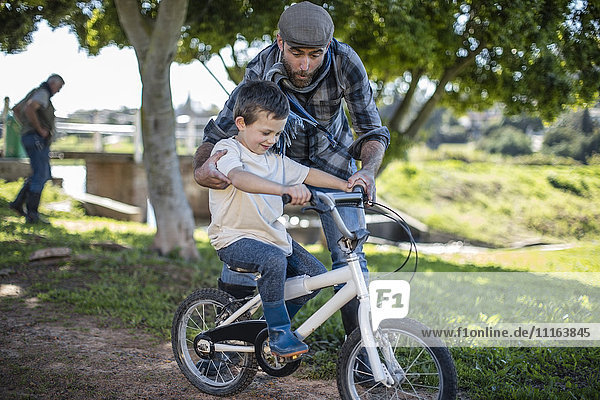 Vater unterstützt Sohn auf dem Fahrrad