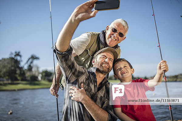 Grandfather  father and son taking a selfie with fishing rods