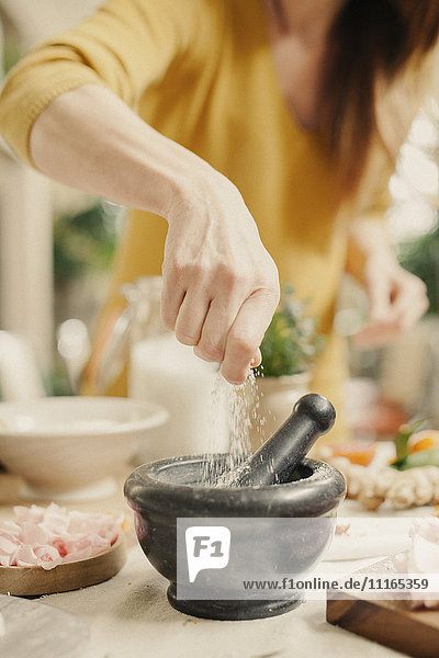 A woman adding ingredients to a pestle and mortar.