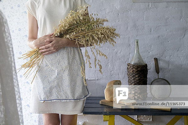 Kaukasische Frau hält Weizenstrauß in der Nähe von geschnittenem Brot