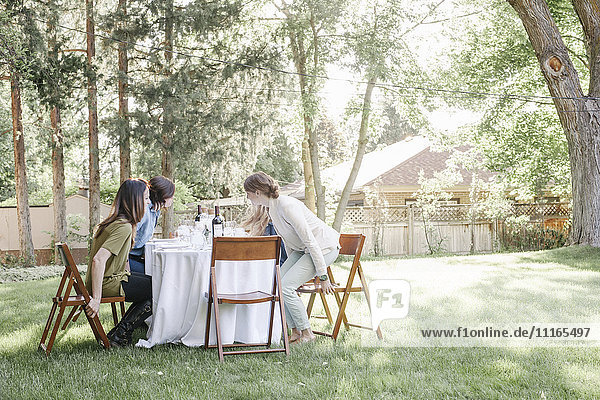 Gruppe von Frauen  die in einem Garten um einen Tisch sitzen.