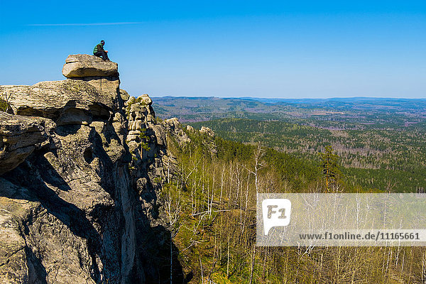 Caucasian man sitting on mountain rock admiring scenic view
