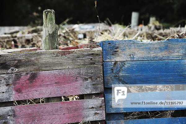 Eine Komposttonne aus alten Holzpaletten  mit toten Blumen  Gartenabfällen und Erde.