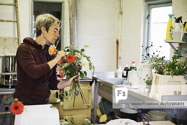Organic flower arrangements. A woman creating a hand tied bouquet.