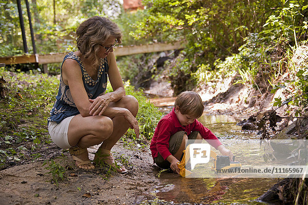 Caucasian mother watching son playing with construction toys in river