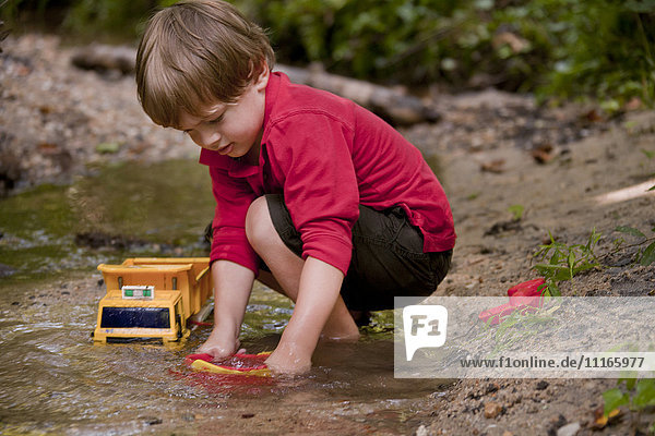 Kaukasischer Junge spielt mit Bauspielzeug im Fluss