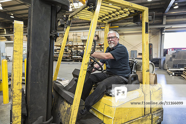 Caucasian worker driving forklift in factory