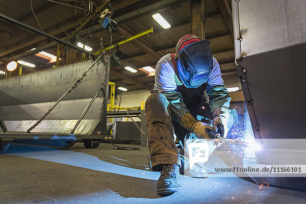 Caucasian man welding metal in factory