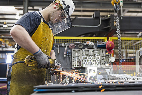 Caucasian worker grinding metal in factory
