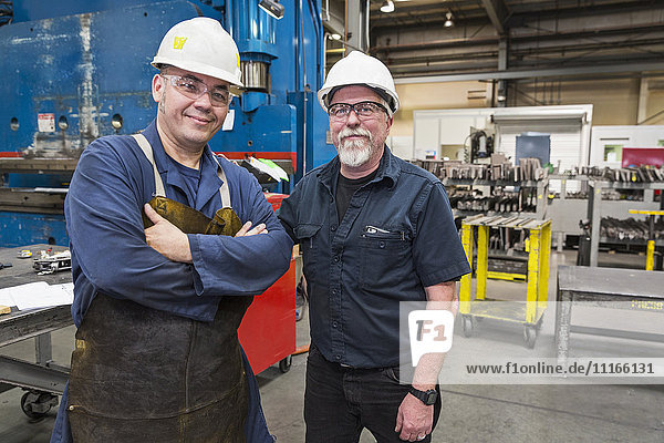 Lächelnde Arbeiter posieren in der Fabrik
