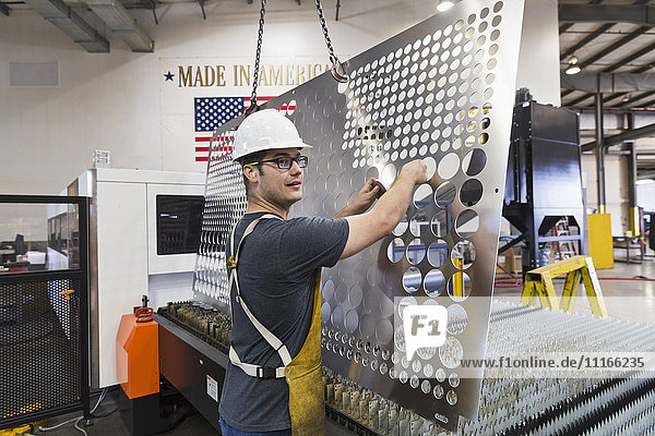 Caucasian worker fabricating metal in factory