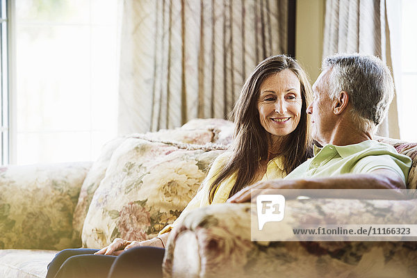 Lächelndes älteres Paar  das auf einem Sofa sitzt.
