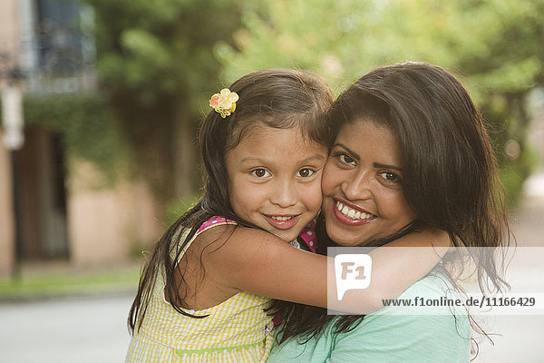 Hispanic mother hugging daughter