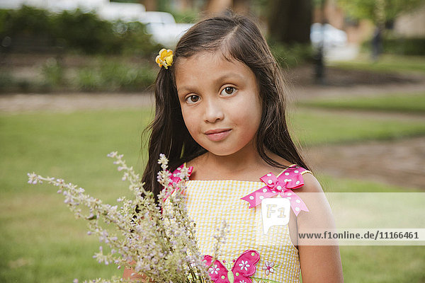 Hispanisches Mädchen hält Blumen im Park