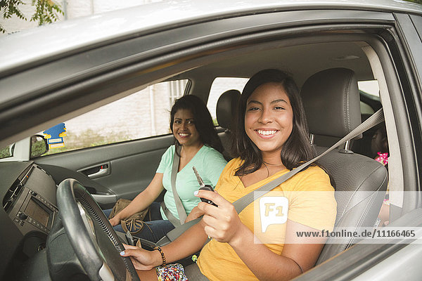 Lächelnde hispanische Mutter und Tochter posieren im Auto