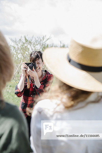 Ein Fotograf  der an einem Sommertag zwei Frauen fotografiert.