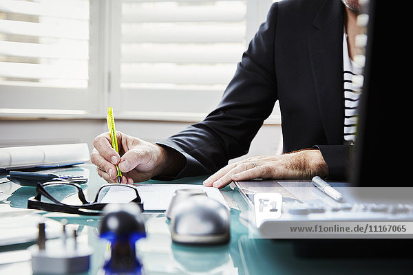 Ein Mann sitzt an einem Schreibtisch in einem Büro und hält einen Stift in der Hand.