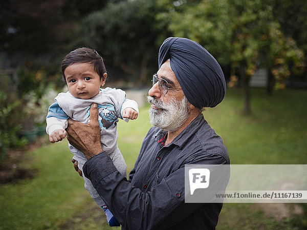 Indischer Großvater hält Baby-Enkel