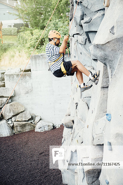 Mixed Race man climbing rock climbing wall
