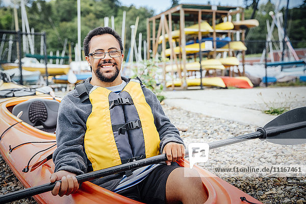 Mixed Rave man sitting in kayak holding paddle