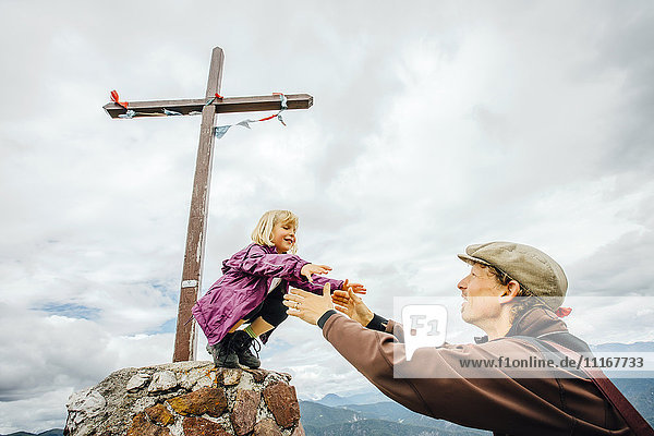 Caucasian father helping daughter on rock at crucifix
