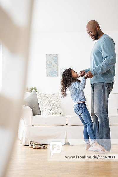 Daughter standing on feet of father and dancing