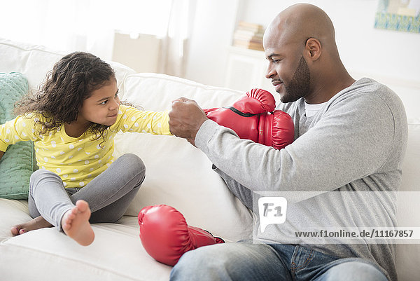 Vater hilft Tochter mit Boxhandschuhen