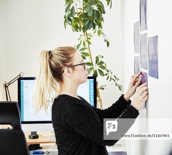 A woman sticking printed notes onto a wall  planning a project and creating a project management plan.