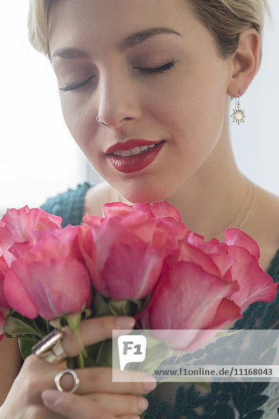Caucasian woman smelling pink roses