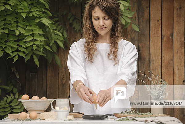 Eine Frau steht an einem Tisch und bereitet Eier zum Frühstück zu.