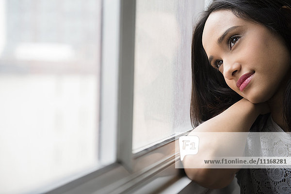 Mixed Race woman daydreaming at window