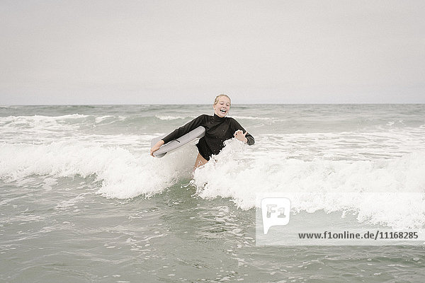 Blondes Mädchen beim Bodyboarding im Meer.