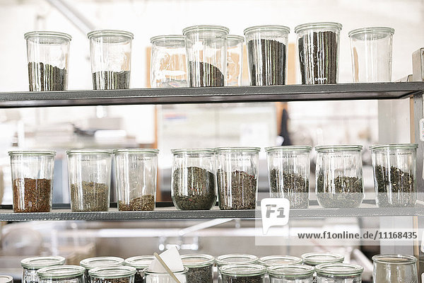 Eine Auswahl an getrockneten Lebensmitteln und Gewürzen in Glasgläsern auf den Regalen eines Cafés.
