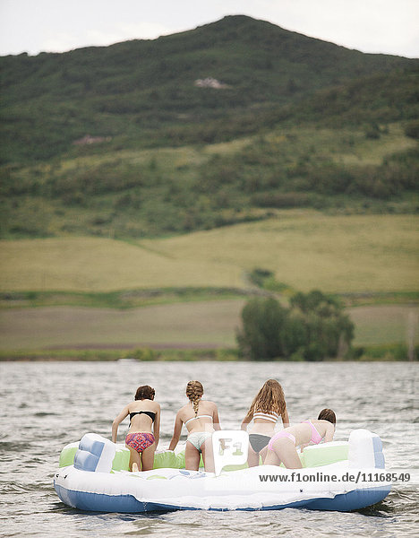 Teenage girls in an inflatable dinghy on a lake.