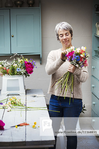 A florist creating a hand tied bunch of fresh flowers.