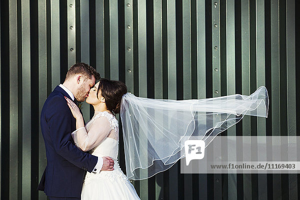 A bride and bridegroom on their wedding day  kissing each other.