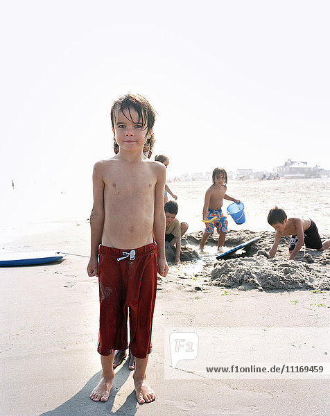 Gruppe von Jungen  die an einem Sandstrand am Meer spielen.