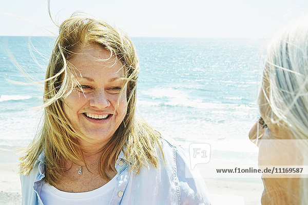 Lächelnde blonde  reife Frauen  die am Meer stehen.