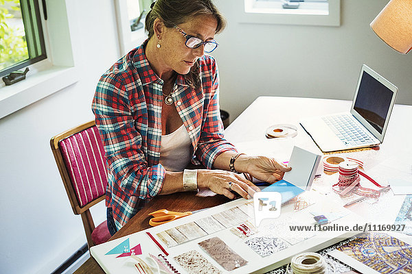 Eine Frau  die mit Material und Papier ein Collagebild erstellt.