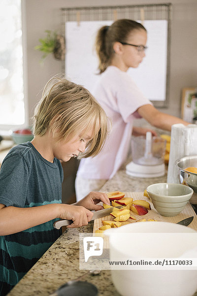 Familie bereitet das Frühstück in einer Küche vor  Junge schneidet Obst.