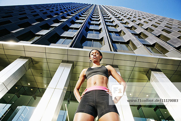 Ernste schwarze Frau unter modernem Gebäude stehend