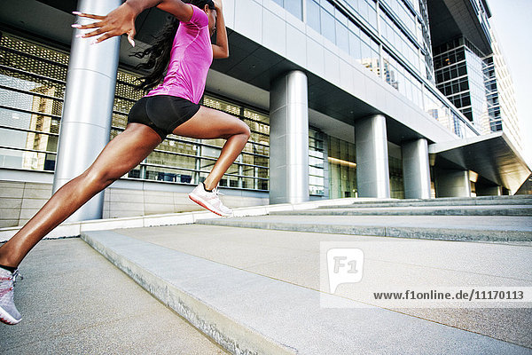Schwarze Frau läuft und springt auf Stadttreppe
