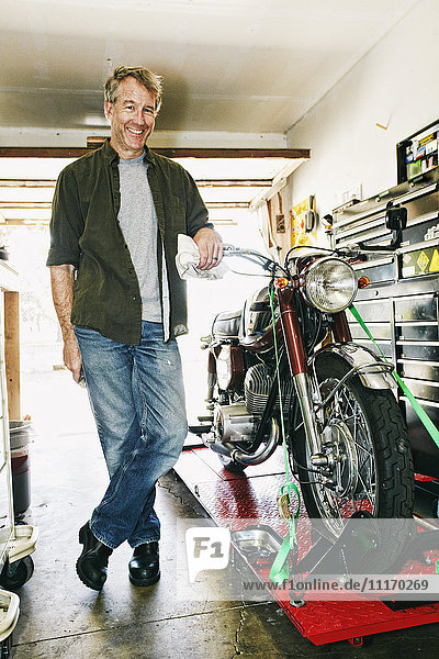 Caucasian man posing with motorcycle in garage