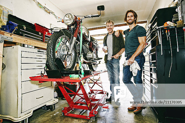Kaukasischer Vater und Sohn reparieren Motorrad in der Garage