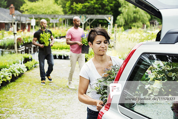 Car parked at a garden centre  a woman loading flowers into the boot.