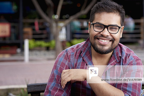 Smiling Hispanic man with beard sitting on bench
