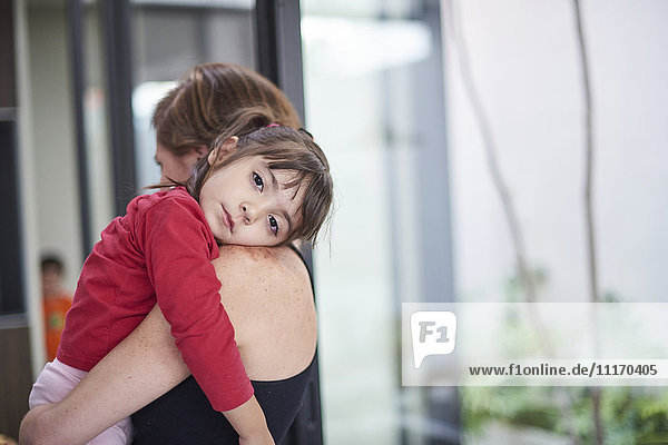 Hispanic mother carrying tired daughter