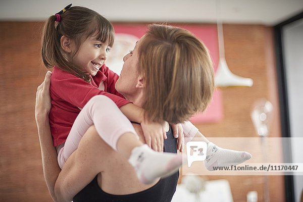 Playful Hispanic mother carrying daughter