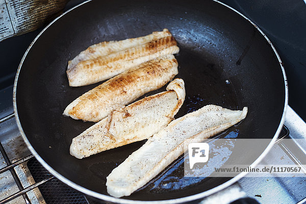 Nahaufnahme von Fischfilets  die in einer Bratpfanne gebraten werden.