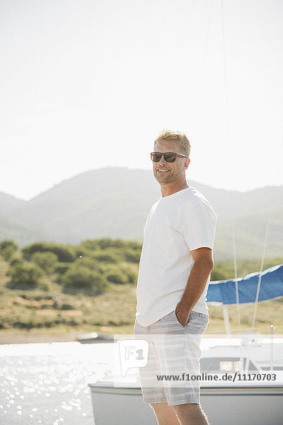 Blond man wearing sunglasses standing on a jetty.